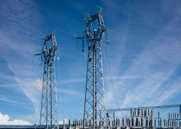 Electric high voltage pylons on Power station electric distribution center over blue sky with streaky clouds, copy space